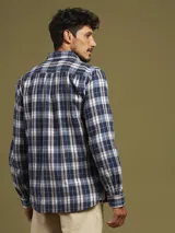 Camisa a cuadros azul marino, con cuello abotonado, manga larga y dos bolsillos con solapa abotonada en el pecho.