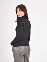 Polera de manga larga ajustada al cuerpo, con cuello alto, confeccionada en tejido suave y elástico de color negro.