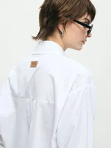 Camisa de manga larga a rayas verticales rojas y blancas, con cuello clásico, bolsillo en el pecho y corte holgado.