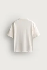 Camiseta de corte relaxed fit, confeccionada en mezcla de algodón y lino, con cuello redondo y mangas cortas.