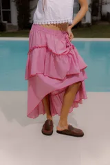 Pollera larga de diseño fluido y asimétrico con estampa de cuadros vichy en color rosado y blanco, con capas y volados terminados con ribete rojo.
