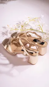 Sandalias de tacón bajo color dorado, con tiras cruzadas en el empeine, pulsera al tobillo con hebilla y plantilla acolchada.