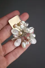 Aros colgantes plateados con forma de flor, adornados con perlas blancas y doradas.