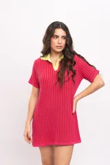 Vestido corto de punto acanalado, color fucsia, con cuello polo y solapa en contraste de color amarillo. Presenta mangas cortas y un diseño recto y relajado.