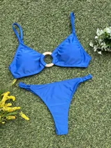 Bikini de dos piezas color azul vibrante. El corpiño es tipo top con un detalle de hebilla redonda dorada en el centro. La bombacha es colaless entera con frunces ajustables en los laterales.