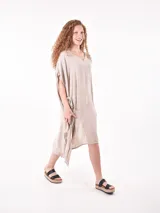 Vestido de tela fluida color marrón medio, con escote en V y mangas cortas tipo kimono. El ruedo es asimétrico con aberturas laterales.