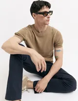 Remera de punto color beige, de manga corta y cuello redondo.