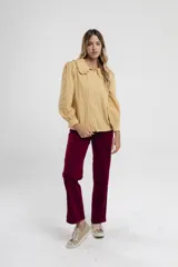 Camisa mostaza de manga larga con cuello babero y botones frontales.