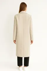 Tapado de paño color negro, de corte recto y largo hasta la rodilla. Presenta cuello con solapas clásicas, cierre frontal con dos botones y bolsillos laterales.