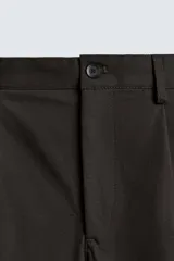 Pantalón de corte regular fit confeccionado en tejido mezcla de algodón. Presenta cintura con detalle de pliegues en el delantero, bolsillos frontales y bolsillos traseros de vivo con botón. Cierre frontal con cremallera y botón.