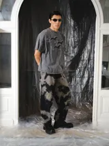Pantalón unisex de denim con diseño amplio y silueta barrel, inspirado en la bombacha de campo y el pantalón sastrero. Cuenta con lavado irregular efecto tie-dye en tonos negro y gris, pinzas delanteras y bolsillos laterales.