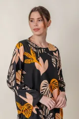 Blusa negra con estampado de hojas color naranja y beige, cuello redondo y mangas 3/4.