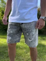Bermuda de jean gris con efecto acid wash y roturas decorativas en el frente.