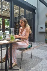 Mono largo a rayas verticales color naranja y blanco, con escote halter y corte ajustado.