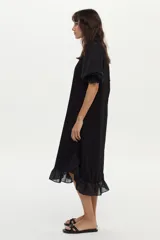 Vestido midi de corte recto color negro, con mangas cortas abullonadas, cuello redondo y detalle de volado en el ruedo.
