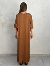 Vestido largo color ladrillo, de corte holgado, con cuello redondo y mangas 3/4 abullonadas.