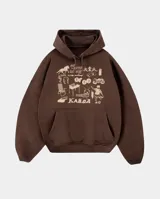 Canguro oversize color marrón chocolate, con capucha y bolsillo frontal tipo canguro. Presenta un estampado gráfico en color crema en el pecho con diversos dibujos y la inscripción 'Más barrio que moda' y 'Kabor'.