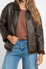 Campera tipo gamulán de corte oversize, color marrón oscuro con efecto cuero envejecido. Presenta cuello solapa, puños y ruedo con forro de corderito sintético en tono marrón oscuro. Cuenta con cierre frontal completo y detalles de costuras reforzadas.