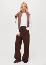 Pantalón de jean estilo wide leg color marrón chocolate, con tiro medio, cinco bolsillos, cierre frontal con cremallera y botón, y detalle de costuras en la cadera.