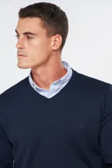 Suéter de tejido fino color azul marino, con cuello en V y manga larga. Presenta un pequeño logo bordado en el pecho.