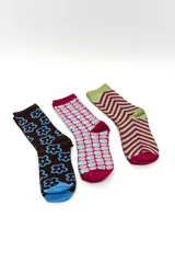 Pack de tres pares de medias largas tipo crew con diseños estampados coloridos: un par marrón con flores celestes, un par rosado con patrón geométrico celeste y un par verde con líneas en zigzag rojas y azules.