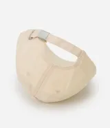 Gorra de algodón color beige con visera curva. Presenta bordado frontal en cursiva negra con la frase "less is more" y pespuntes contrastantes en negro a lo largo del borde de la visera. Cuenta con cierre ajustable en la parte posterior mediante hebilla metálica.