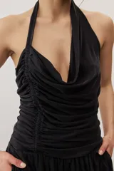 Top negro con diseño cruzado tipo halter, escote pronunciado y fruncido lateral.