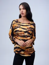 Blusa de gasa satén estampada con diseño animal print en tonos naranja y negro, de la marca Ninety. Tiene mangas tres cuartos y cuello redondo.