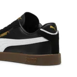 Championes Puma Club II Era, color negro con franja lateral blanca y suela de goma color caramelo. Presenta detalles en dorado en el logo lateral y lengüeta.