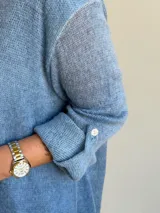 Sweater de punto color azul jean, con cuello redondo, mangas largas con vuelta y diseño amplio de corte evasé.