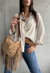 Camisa de color beige con cuello clásico, cierre frontal de botones y mangas largas con puños doblados. Presenta un delicado bordado floral en las mangas.