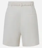 Short de sastre color blanco, tiro alto, corte recto y holgado, con trabillas en la cintura y cinturón elástico con hebilla dorada. Presenta bolsillos falsos en la parte trasera.