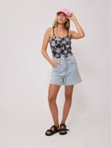 Gorra de lona color crema con visera celeste. Presenta bordado frontal en hilo azul claro con el texto "Rusty Tribe" y un pequeño diseño de flores.