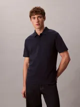 Chomba de manga corta Calvin Klein confeccionada en algodón interlock, con cuello clásico y cierre frontal de botones. Presenta un diseño liso en color azul marino con el logo de la marca sutilmente bordado en el pecho.