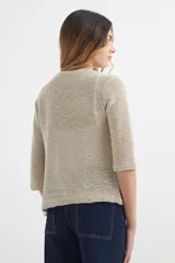 Cardigan verde esmeralda de tejido de punto calado, con mangas 3/4 y corte evasé. Presenta cuello redondo con abertura en forma de gota y cierre con un único botón.