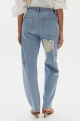 Pantalón estilo cargo confeccionado en denim celeste, de corte recto y holgado. Presenta apliques decorativos circulares de crochet en tonos beige en los laterales y bolsillos utilitarios.