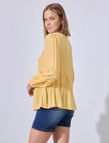 Blusa de gasa color amarillo, con apliques de puntilla en el frente, manga larga con puño elastizado y escote en V.