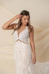 Vestido de novia largo de encaje color marfil con fondo de tul color nude, escote en V y cola de encaje con terminación de blonda.