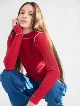 Polera de manga larga confeccionada en tela rib color bordó, con cuello alto y hombreras. Presenta costuras a la vista con pespuntes en hilo de color contrastante en el cuello, puños, hombros y ruedo.