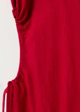 Vestido midi color rojo, sin mangas, con cuello redondo y aberturas laterales en la cintura con tiras ajustables.