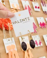 Aros de argolla dorada con dije colgante de piedra ovalada en color marrón oscuro con textura estriada.