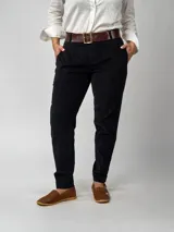 Pantalón de pana negro de corte recto, con bolsillos laterales y traseros. Se ajusta a la cintura con cinturón de cuero negro.