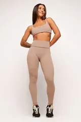 Conjunto deportivo de top y calzas color tostado, confeccionado en poliamida de alta performance con detalles de vivo contrastante. El top cuenta con breteles anchos y diseño slim, mientras que la calza presenta un diseño minimalista de tiro alto.
