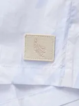 Camisa celeste con estampado de remolinos blancos, de corte recto, manga corta y cuello cubano.