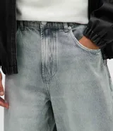 Pantalón de jean color gris claro con efecto desteñido, de corte muy ancho y holgado estilo baggy, tiro medio y bolsillos funcionales.
