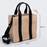Cartera tipo tote bag Melissa modelo Dulce Bag, de color beige con acabado brillante, doble asa de mano negra y correa ajustable para hombro. Las asas principales incorporan bandas negras con el logotipo de la marca grabado.