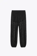 Pantalón negro de tiro alto, confeccionado en encaje transparente con diseño floral. Posee cintura elástica y bajo abullonado con elástico. Incluye forro interior tipo shorts.