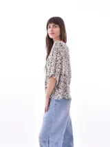 Blusa blanca de mangas cortas, con cuello redondo y abotonada al frente.