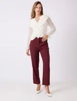 Pantalón sastrero color bordó, de corte recto y tiro alto, con largo al tobillo. Tiene pretina limpia con cierre de broche interno y cremallera, pasadores para cinturón y bolsillos funcionales en la parte delantera.