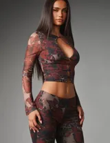 Conjunto de dos piezas de mesh elastizado con estampado floral y animal print, compuesto por un top corto de manga larga con cierre frontal de botones y abertura tipo lágrima, y un pantalón capri de tiro medio y calce ajustado.